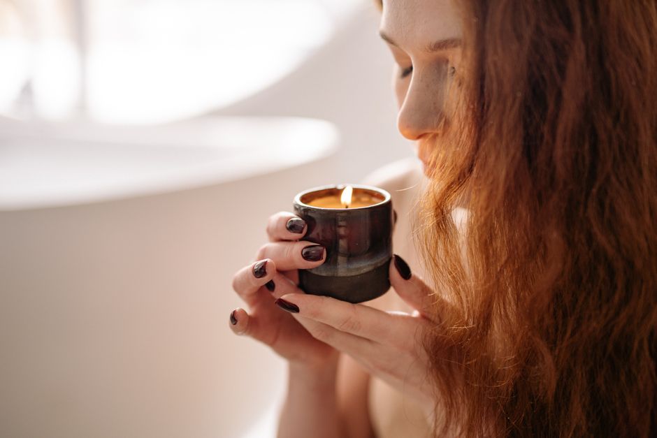 Mujer disfrutando del aroma de una vela perfumada